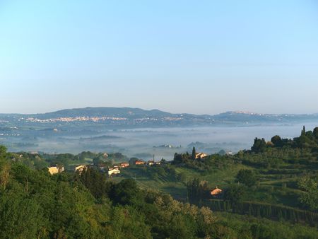 Fabulous landscape of the foggy morning in Tuscany. The valley between Montepulciano and Chiusiの写真素材