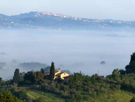 Fabulous landscape of the foggy morning in Tuscany. The valley between Montepulciano and Chiusiの写真素材