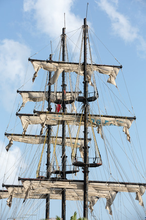 Masts and sails of huge sailing boat against the background of blue sky 