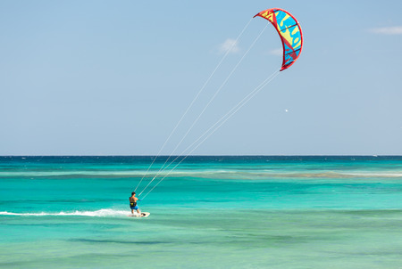 Unknown kitesurfer surfing on a flat azure water of Atlantic ocean in Corralejo, Fuerteventura, Canary islands, Spainのeditorial素材