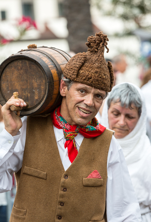 FUNCHAL, MADEIRA, PORTUGAL - SEPTEMBER 4, 2016: Man carry the barrel of wine in traditional costume  durnig historical and ethnographic  parade of Madeira Wine Festival in Funchal. Madeira, Portugalのeditorial素材
