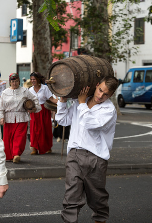 FUNCHAL, MADEIRA, PORTUGAL - SEPTEMBER 4, 2016: Man carry the barrel of wine in traditional costume  durnig historical and ethnographic  parade of Madeira Wine Festival in Funchal. Madeira, Portugalのeditorial素材