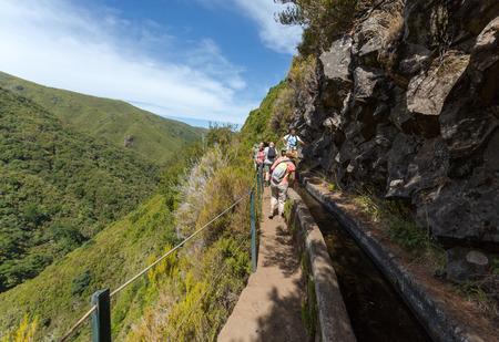 Tourist is walking  along irrigation canals. Historic water supply system, known as Levada in tropical forest, Madeira Island, Portugalの写真素材
