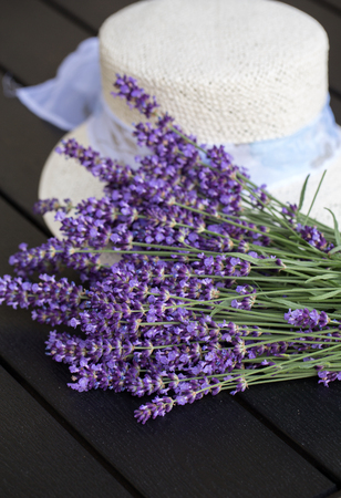 Lavender flowers and white hat on black tableの写真素材