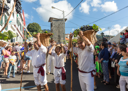 ESTREITO DE CAMARA DE LOBOS, PORTUGAL - SEPTEMBER 10, 2016: Men carrying baskets of grapes wearing in traditional costumes at Madeira Wine Festival in Estreito de Camara de Lobos, Madeira, Portugal. The Madeira Wine Festival honors the grape harvest with のeditorial素材