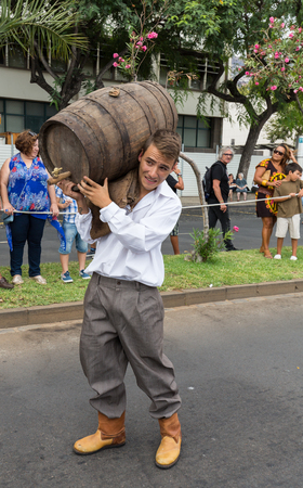 FUNCHAL, MADEIRA, PORTUGAL - SEPTEMBER 4, 2016: Man carry the barrel of wine in traditional costume  durnig historical and ethnographic  parade of Madeira Wine Festival in Funchal. Madeira, Portugalのeditorial素材