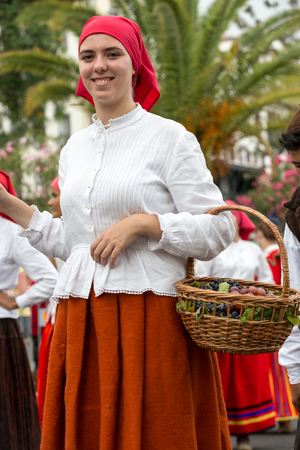 FUNCHAL, PORTUGAL - SEPTEMBER 4, 2016:  women in traditional costume carry the basket of grapes durnig historical and ethnographic  parade of Madeira Wine Festival in Funchal. Madeira, Portugallのeditorial素材