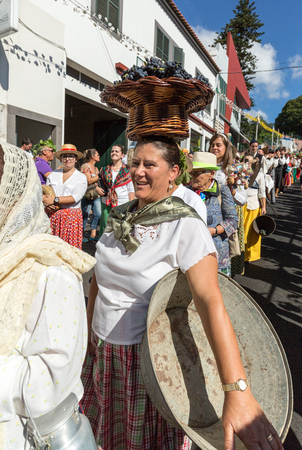 ESTREITO DE CAMARA DE LOBOS, PORTUGAL - SEPTEMBER 10, 2016: Woman wearing in traditional costume with a basket of grapes on her head at Madeira Wine Festival in Estreito de Camara de Lobos, Madeira, Portugalのeditorial素材