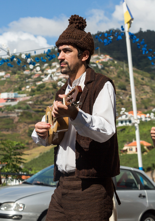 ESTREITO DE CAMARA DE LOBOS, PORTUGAL - SEPTEMBER 10, 2016: Folk music group in local costumes performs  a folk dance at Madeira Wine Festival in Esterito de Camara de Lobos on the Madeira, Portugal. The Madeira Wine Festival honors the grape harvest withのeditorial素材