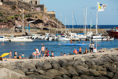 MACHICO, MADEIRA, PORTUGAL - SEPTEMBER 11, 2016: People are resting on a sunny day at the beach in Machico. Madeira Island, Portugalのeditorial素材