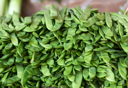 Fresh green beans piled up at a market vegetable stall 