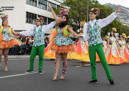 Funchal; Madeira; Portugal - April 22; 2018: A group of people in colorful costumes are dancing at Madeira Flower Festival Parade in Funchal on the Island of Madeira. Portugal.のeditorial素材