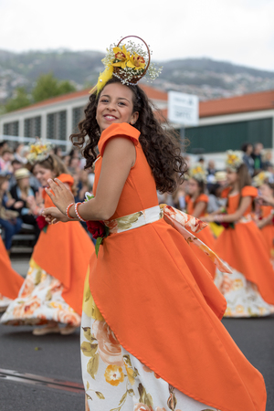 Funchal; Madeira; Portugal - April 22; 2018: A group of girls in orange costumes are dancing at Madeira Flower Festival Parade in Funchal on the Island of Madeira. Portugal.のeditorial素材