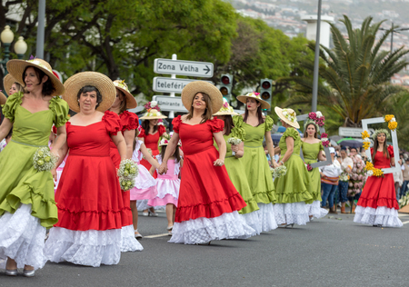 Funchal; Madeira; Portugal - April 22; 2018: A group of women in red and green dresses are dancing at Madeira Flower Festival Parade in Funchal on the Island of Madeira. Portugal.のeditorial素材
