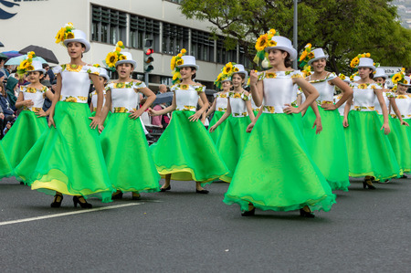 Funchal; Madeira; Portugal - April 22; 2018: A group of girls in colorful dresses with sunflowers motifs are dancing at Madeira Flower Festival Parade in Funchal on the Island of Madeira. Portugal.のeditorial素材