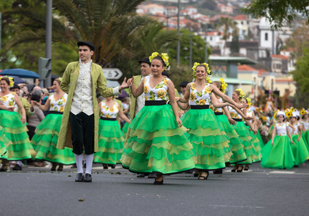 Funchal; Madeira; Portugal - April 22; 2018: a group of people  in colorful dresses with sunflowers motifs are dancing at Madeira Flower Festival Parade in Funchal on the Island of Madeira. Portugal.のeditorial素材