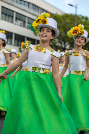 Funchal; Madeira; Portugal - April 22; 2018: A group of girls in colorful dresses with sunflowers motifs are dancing at Madeira Flower Festival Parade in Funchal on the Island of Madeira. Portugal.のeditorial素材