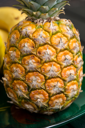 Ripe, fresh pineapple isolated on green plateの写真素材