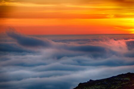 Dreamy misty landscape above the sea of clouds, mountains at sunset in Iceland