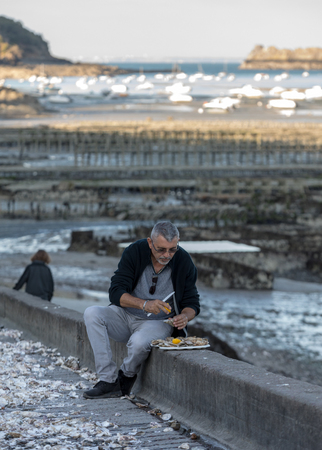 Cancale, France - September 13, 2018: Man eating oysters bought on the seafront at Cancale, Brittany, Franceのeditorial素材