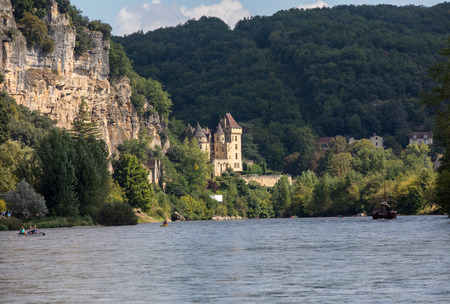 La Roque-Gageac, Dordogne, France - September 7, 2018: Canoeing and tourist boat, in French called gabare, on the river Dordogne at La Roque-Gageac and Chateau La Malartrie in the background. Aquitaine, Franceのeditorial素材
