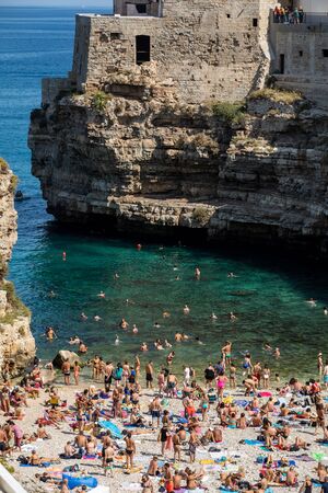 Polignano, Italy - September 17, 2019: People relax and swimming on lovely beach Lama Monachile in Polignano a Mare, Adriatic Sea, Apulia, Bari province, Italy,のeditorial素材