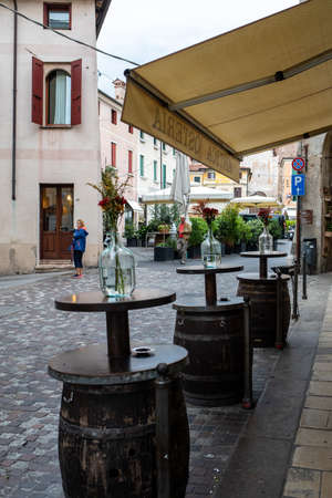Bassano del Grappa, Italy  - September 6, 2019: Typical street scene, with cafe tables, local and...