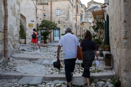 Matera, Italy - September 14, 2019: Tourists during a walk on Cobblestone street in the Sassi di Matera a historic district in the city of Matera. Basilicata. Italyの写真素材