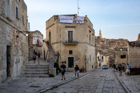 Matera, Italy - September 18, 2019: Tourists during a walk on Cobblestone street in the Sassi di Matera a historic district in the city of Matera. Basilicata. Italyのeditorial素材