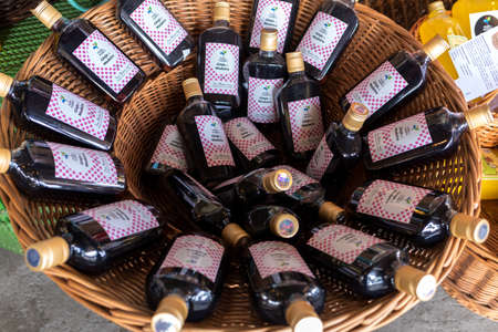 Funchal, Madeira, Portugal - April 19, 2018: Bottles of Ginja da Madeira in a wicker basket at a street market stall in Funchal, Madeira. Portugal.のeditorial素材