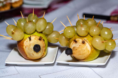 Fruit dessert. Hedgehog made of pears and grapesの写真素材