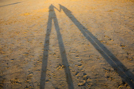 Long shadows of a walking couple on lovely beach in Saint Malo. Brittany, France