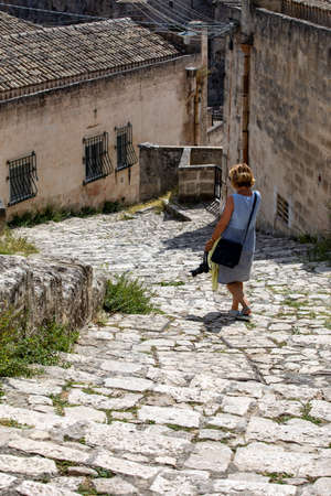 Matera, Italy - September 15, 2019: Woman during a walk on Cobblestone street in the Sassi di Matera a historic district in the city of Matera. Basilicata. Italyのeditorial素材