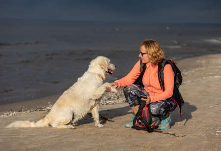 Stegna, Poland - September 4, 2020: A woman walking with her golden retriever on the beach in Stegnaのeditorial素材