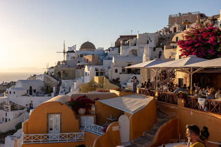 Oia, Santorini, Greece - June 28, 2021: Whitewashed houses and windmills in Oia in warm rays of sunset on Santorini island. Greeceのeditorial素材