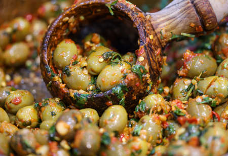 green olives in herbal marinade in an old wooden bowlの写真素材