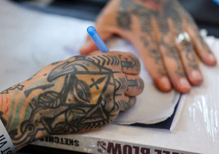 Krakow, Poland - June 11, 2022: 15th Tattoofest in Cracow. One of the most prestigious tattoo festivals. Tattoo artist at work.のeditorial素材