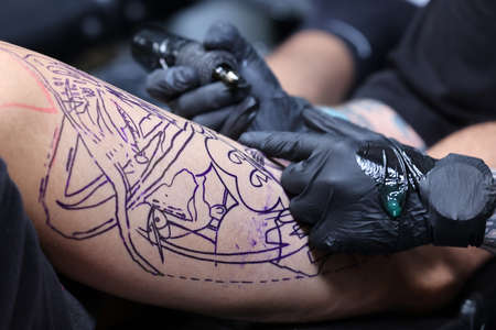 Krakow, Poland - June 11, 2022: 15th Tattoofest in Cracow. One of the most prestigious tattoo festivals. Tattoo artist at work. The process of tattooing.のeditorial素材