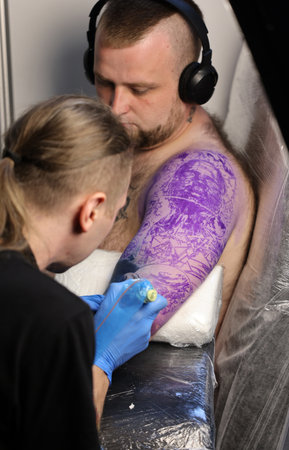Krakow, Poland - June 11, 2022: Unidentified participant at 15th Tattoofest Convention in Cracow. One of the most prestigious tattoo festivals. Tattoo artist at work.のeditorial素材