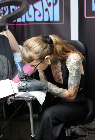 Krakow, Poland - June 12, 2022: Unidentified participant at 15th Tattoofest Convention in Cracow. Tattoo artist at work.のeditorial素材