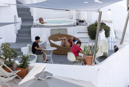 Oia, Santorini, Greece - June 28, 2021: Full relaxation in whitewashed apartments with terraces and pools and a beautiful view in Oia on Santorini island, Greeceのeditorial素材