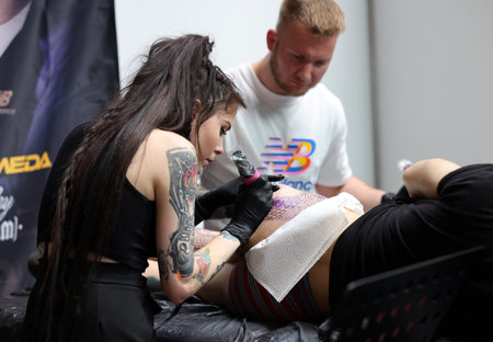 Krakow, Poland - June 11, 2022: Unidentified participant at 15th Tattoofest Convention in Cracow. One of the most prestigious tattoo festivals. Tattoo artist at work.のeditorial素材
