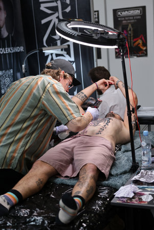 Krakow, Poland - June 12, 2022: Unidentified participant at 15th Tattoofest Convention in Cracow. One of the most prestigious tattoo festivals. Tattoo artist at work.のeditorial素材