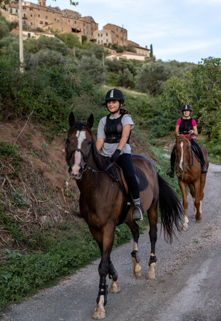 Montemassi, Italy - September 13, 2022: Two girls during a horseback ride on a gravel road in Montemassi, Italyのeditorial素材