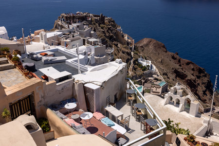Oia, Santorini, Greece - July 3, 2021: Whitewashed buildings and the ruins of Castle of Agios Nikolaos on the edge of the caldera cliff, Oia village, Santorini, Greeceのeditorial素材