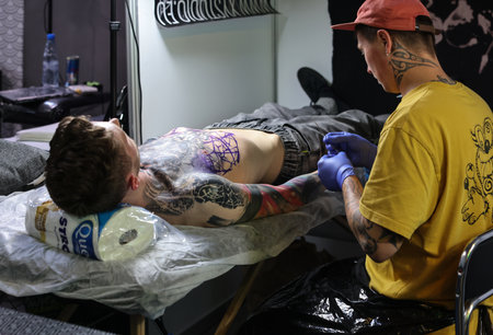 Krakow, Poland - June 12, 2022: Unidentified participant at 15th Tattoofest Convention in Cracow. One of the most prestigious tattoo festivals. Tattoo artist at work.のeditorial素材
