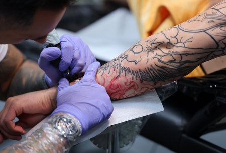 Krakow, Poland - June 12, 2022: Unidentified participant at 15th Tattoofest Convention in Cracow. One of the most prestigious tattoo festivals. Tattoo artist at work.のeditorial素材