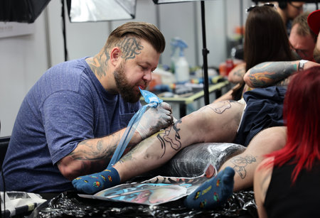 Krakow, Poland - June 11, 2022: Unidentified participant at 15th Tattoofest Convention in Cracow. One of the most prestigious tattoo festivals. Tattoo artist at work.のeditorial素材