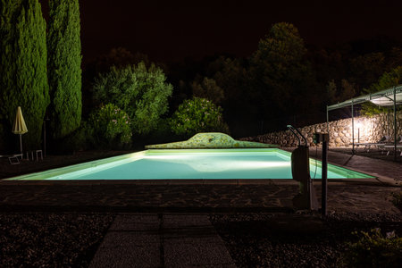 Illuminated swimming pool on the Montemassi hillside surrounded by cypresses and oleanders n the province of Grosseto. Italyの写真素材