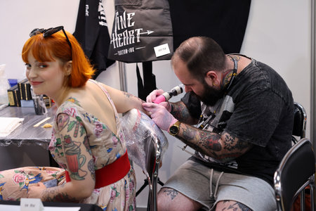 Krakow, Poland - June 12, 2022: Unidentified participant at 15th Tattoofest Convention in Cracow. Tattoo artist at work.のeditorial素材